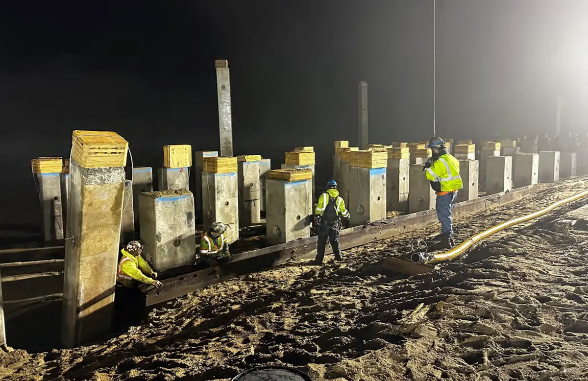 Night work with workers standing by concrete pylons