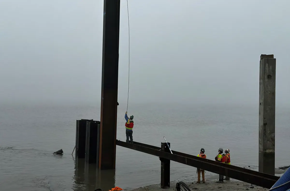 Workers working in foggy conditions along waters edge